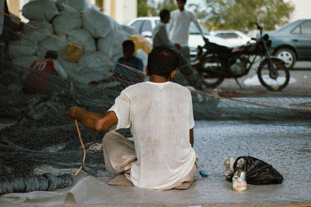 Elderly fisherman mending nets at a Danish harbour